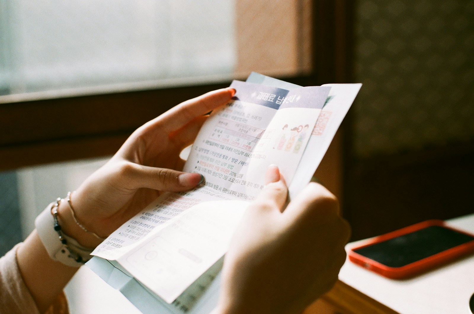 Analyst holding printed records and checking utility data with pen and calculator