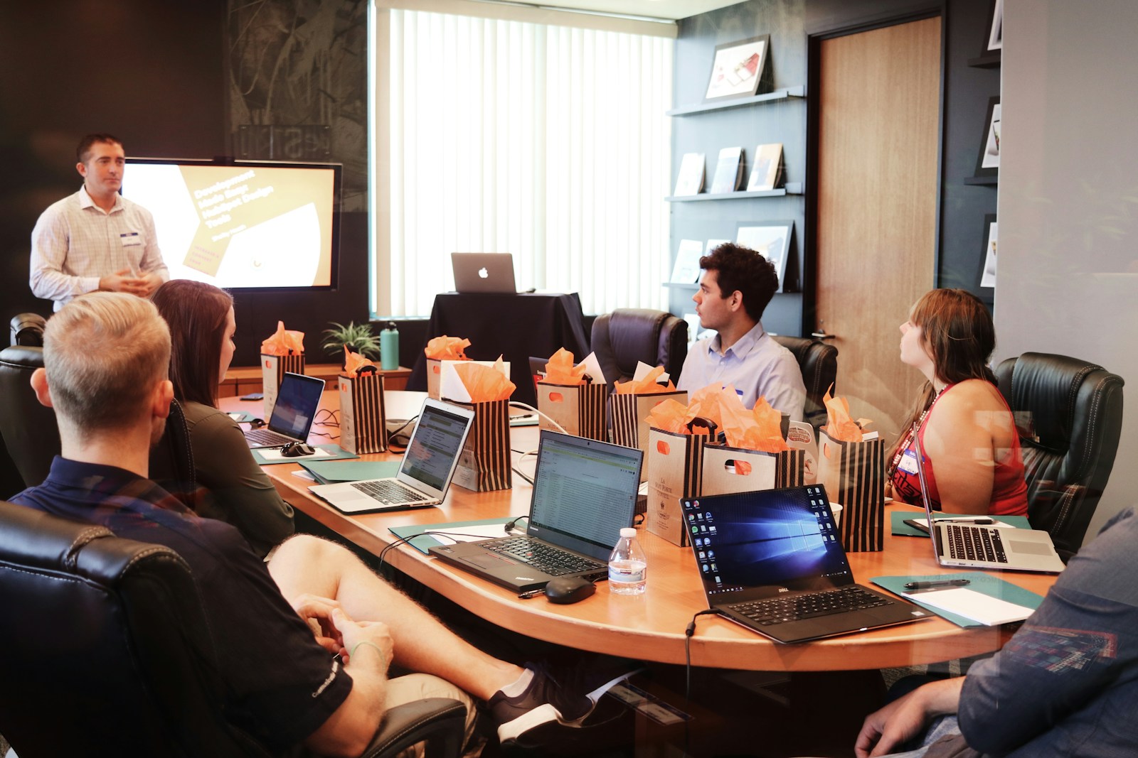 Presenter standing before colleagues reviewing strategy plans with laptops in a meeting