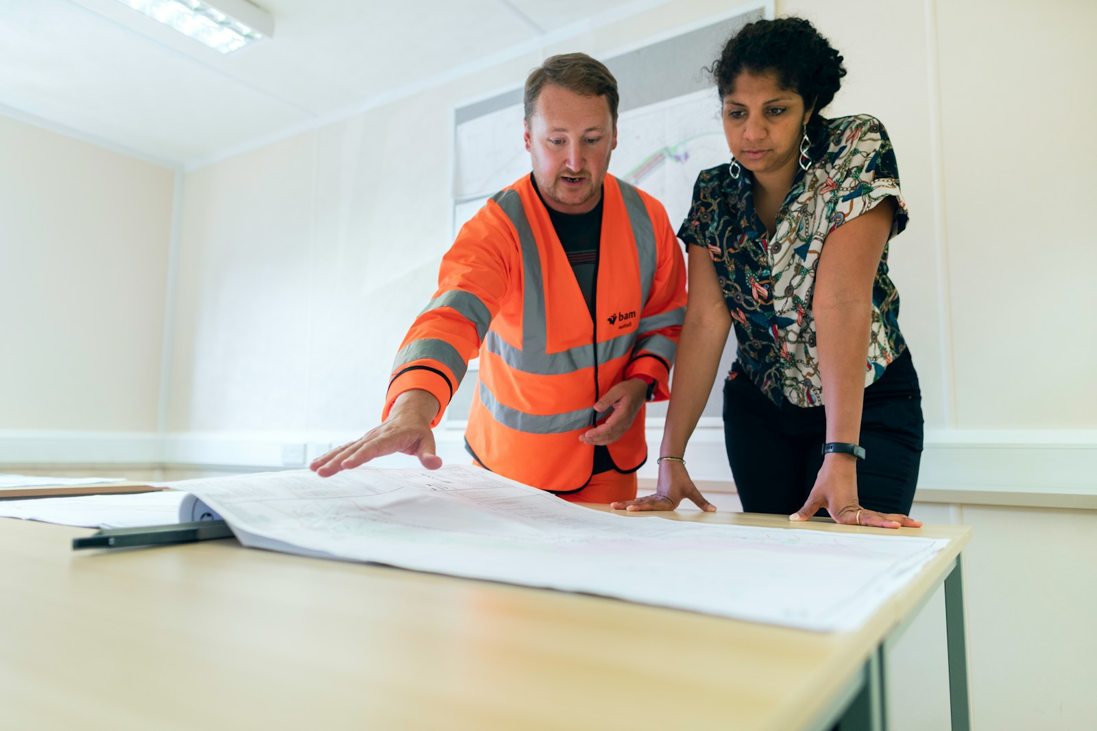 Civil engineer discussing flood risk management plans with a colleague over documents