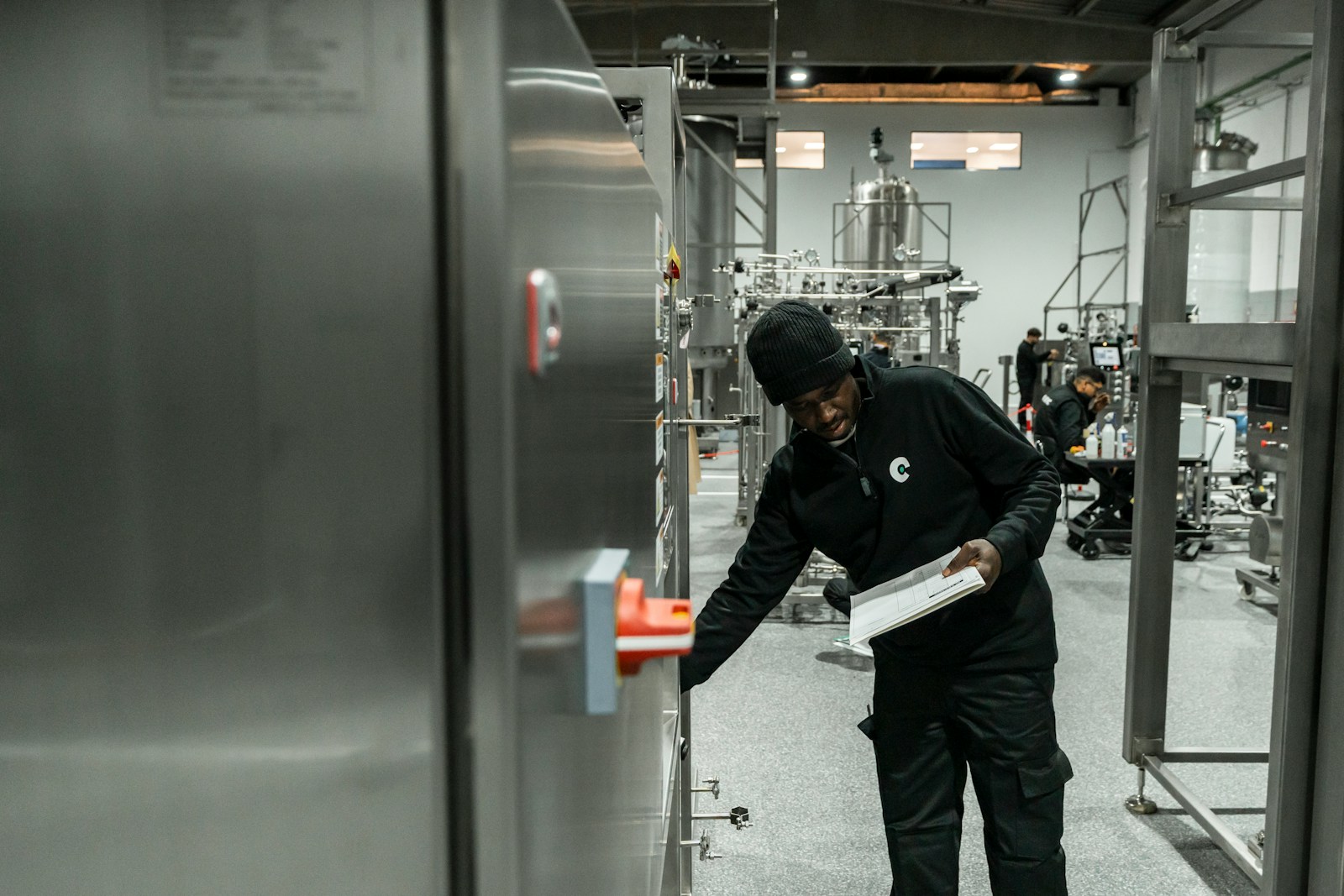 Technician inspecting industrial plant equipment while holding a checklist