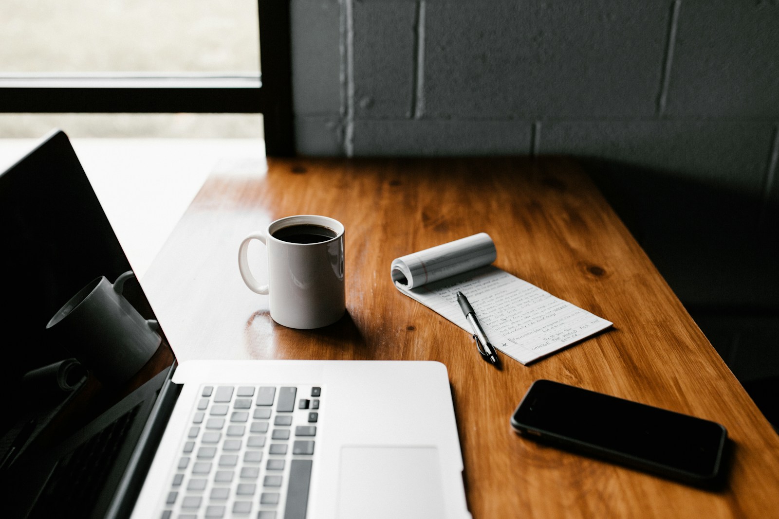 Laptop and notepad on a desk representing structured reporting files